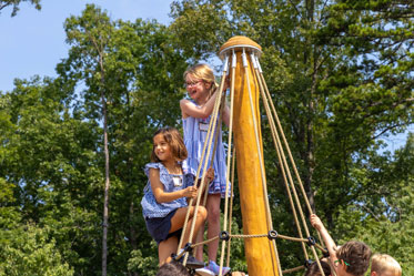 Two girls climb to the top of the mast of a playground ship. Links to Gifts by Estate Note