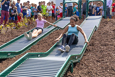 Students racing down two slides while others cheer them on. Links to Beneficiary Designations