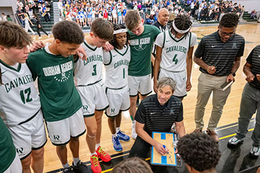 A coach going over the next play with his team. Links to Over Age 65