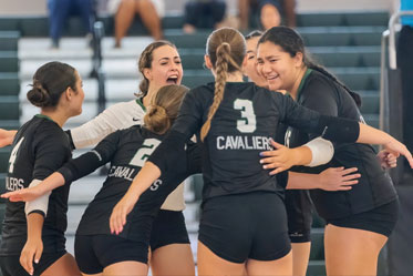 Female students happily gathering in a group hug during a sports event. Links to Gifts by Will