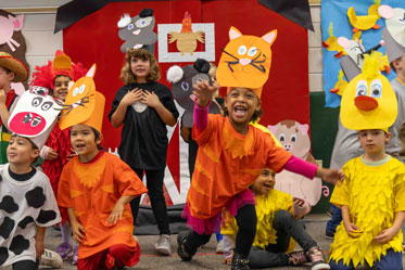Students happily perform a school play, wearing cute, handmade costumes. Links to Gifts That Protect Your Assets